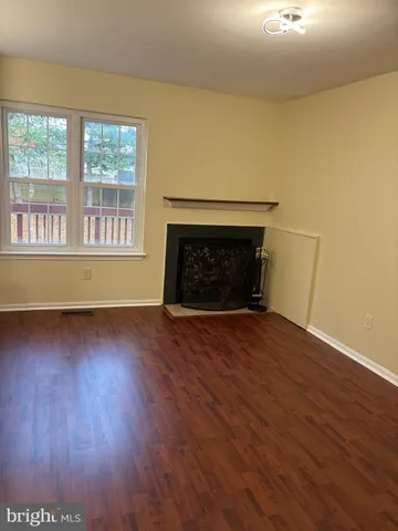 an empty room with wooden floor fire place and windows