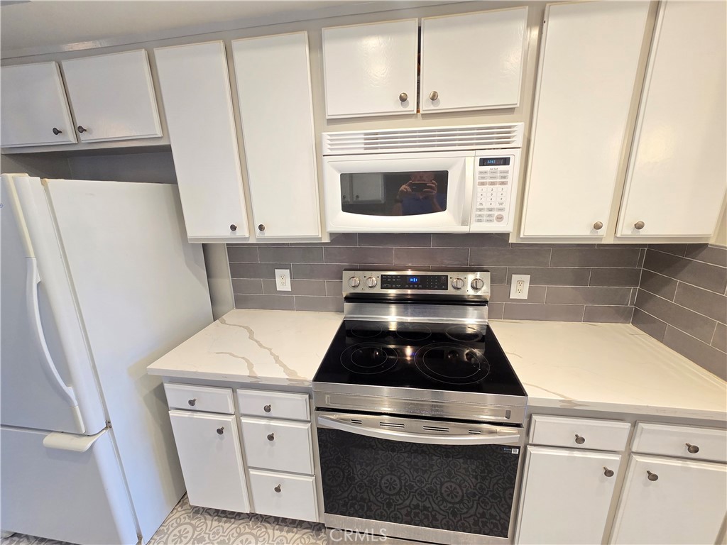 8828 Pershing Drive, Unit 121 Playa del Rey, CA 90293 - Photo 4 of 54 a kitchen with white cabinets and white appliances