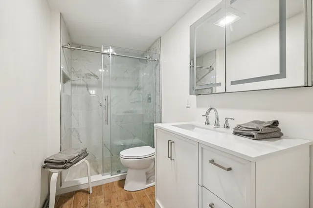 a bathroom with a granite countertop sink a toilet and a shower