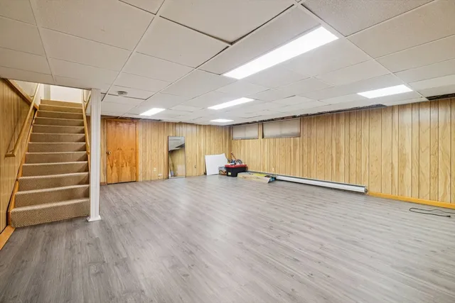 an empty room with wooden floor stairs and a window