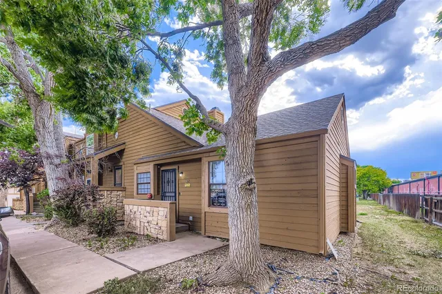 a front view of a house with a yard and large tree