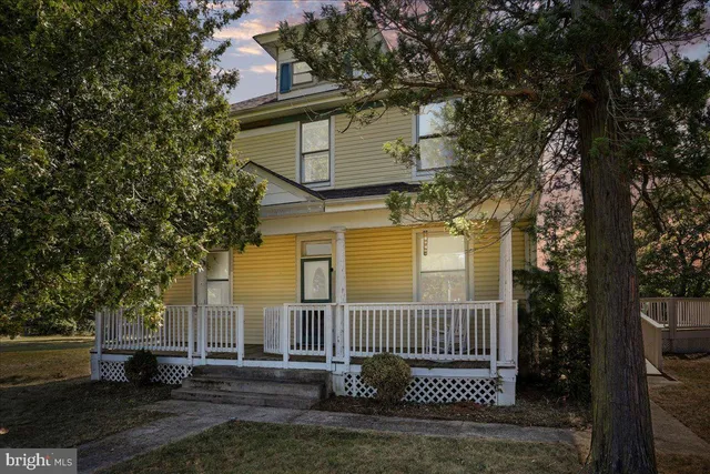 a view of a brick house with a small yard and large trees