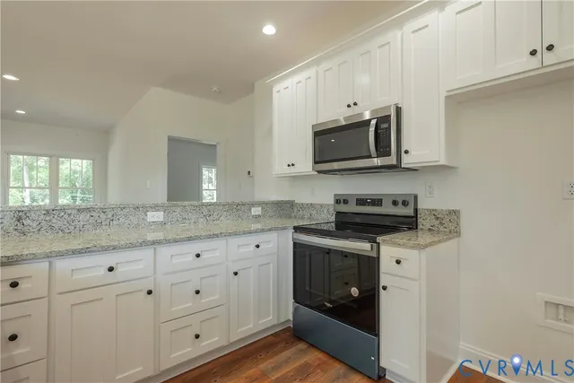 a kitchen with granite countertop white cabinets and a stove a oven with white countertops