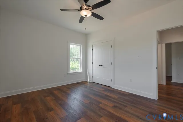 an empty room with wooden floor chandelier fan and windows