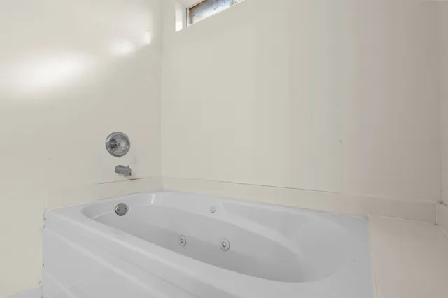 an empty room with windows and chandelier fan