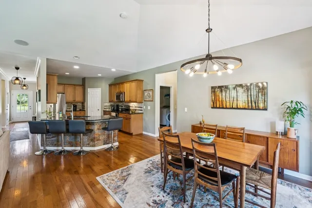 a dining room with wooden floor a chandelier a wooden table and chairs