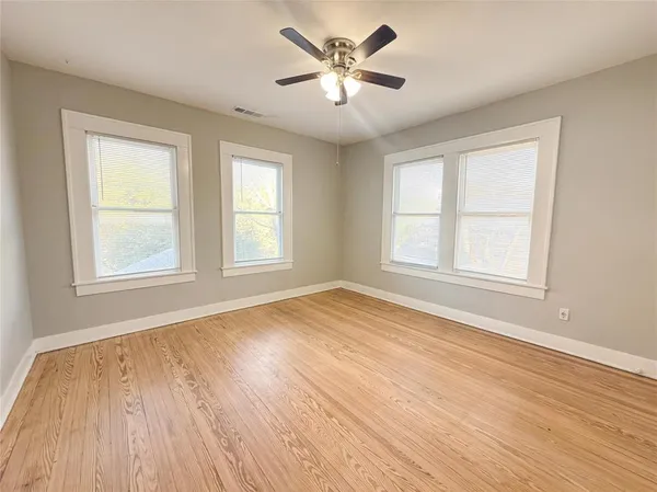 a view of an empty room with a window and wooden floor