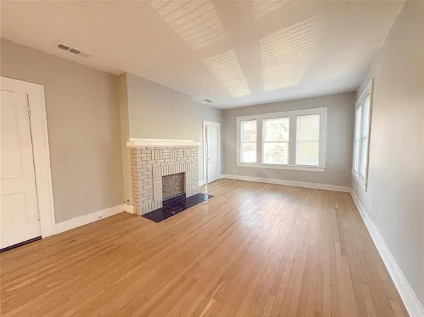 a view of empty room with wooden floor and fireplace
