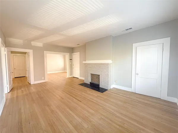a view of empty room with wooden floor and fireplace