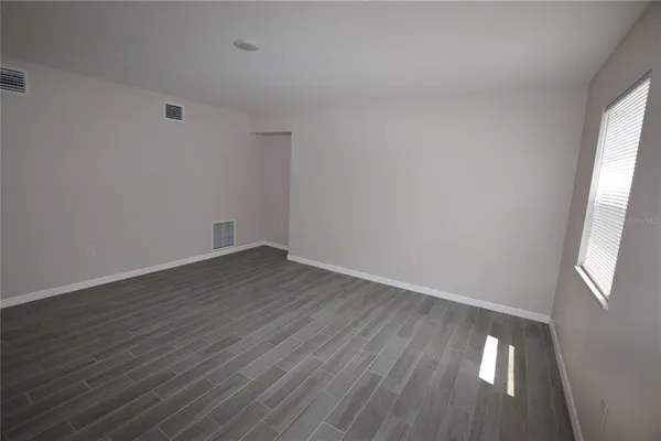 a view of an empty room with wooden floor and a window