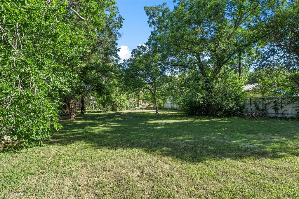 2225 Mitchell Avenue Waco, TX 76708 - Photo 15 of 16 Expansive grassy lawn surrounded by mature trees, featuring a tree-lined perimeter and a partial privacy fence