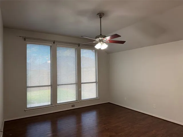 an empty room with wooden floor chandelier and windows