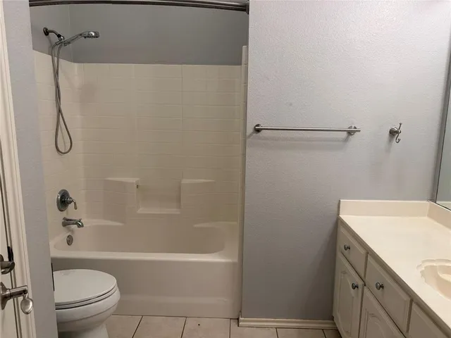 a bathroom with a granite countertop bathtub shower sink vanity and toilet