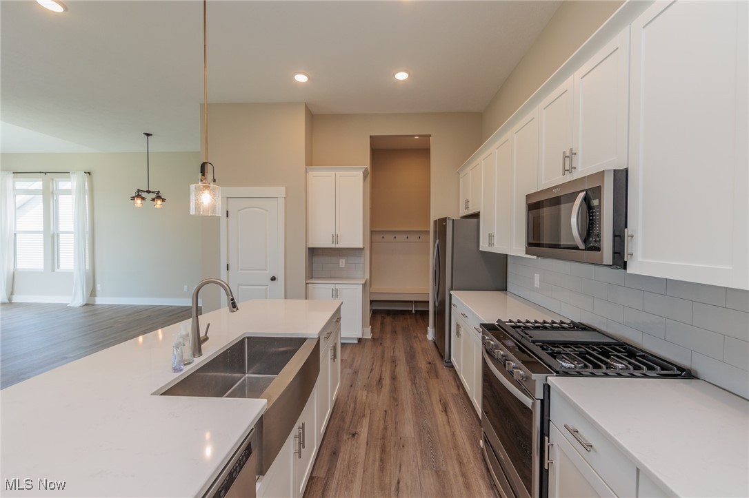 36458 Appian Way North Ridgeville, OH 44039 - Photo 13 of 37 Kitchen featuring white cabinets, decorative backsplash, stainless steel appliances, and light hardwood / wood-style floors