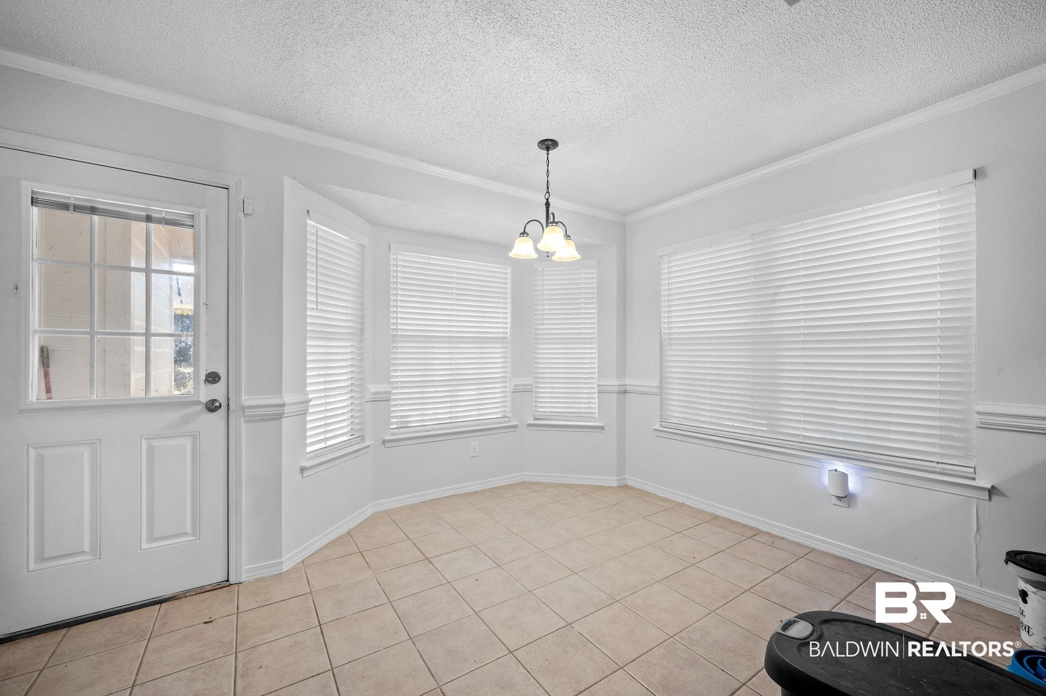 6705 Autumn Ridge Drive Mobile, AL 36695 - Photo 6 of 24 Unfurnished dining area with crown molding, light tile patterned floors, a healthy amount of sunlight, and a notable chandelier