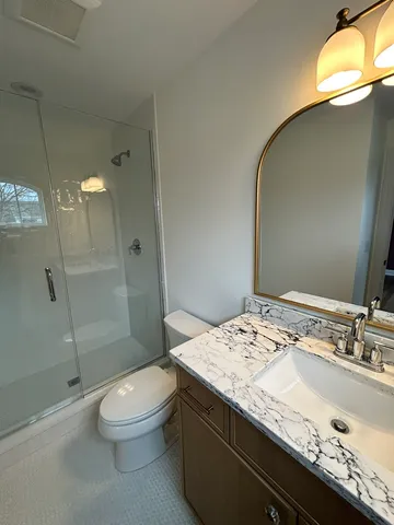 a bathroom with a granite countertop sink a toilet and shower