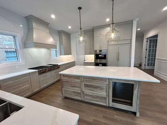a kitchen with kitchen island a counter top space a sink stainless steel appliances and a chandelier