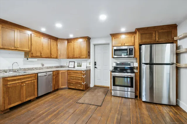 a kitchen with granite countertop wooden floors stainless steel appliances and cabinets