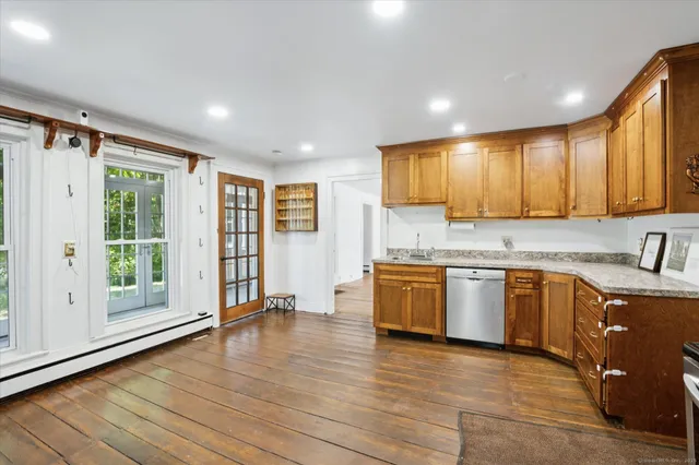 a kitchen with stainless steel appliances granite countertop a stove top oven a sink dishwasher a refrigerator and cabinets with wooden floor