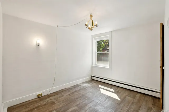 an empty room with wooden floor chandelier and windows