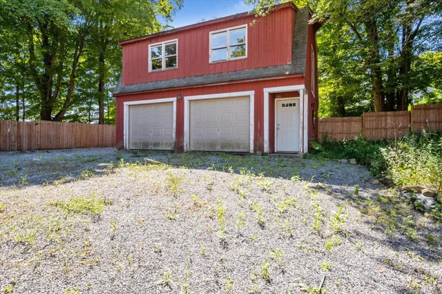 a view of a small house with a yard and large tree