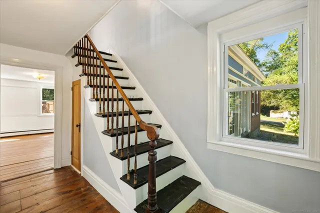 a view of staircase with wooden floor and white walls