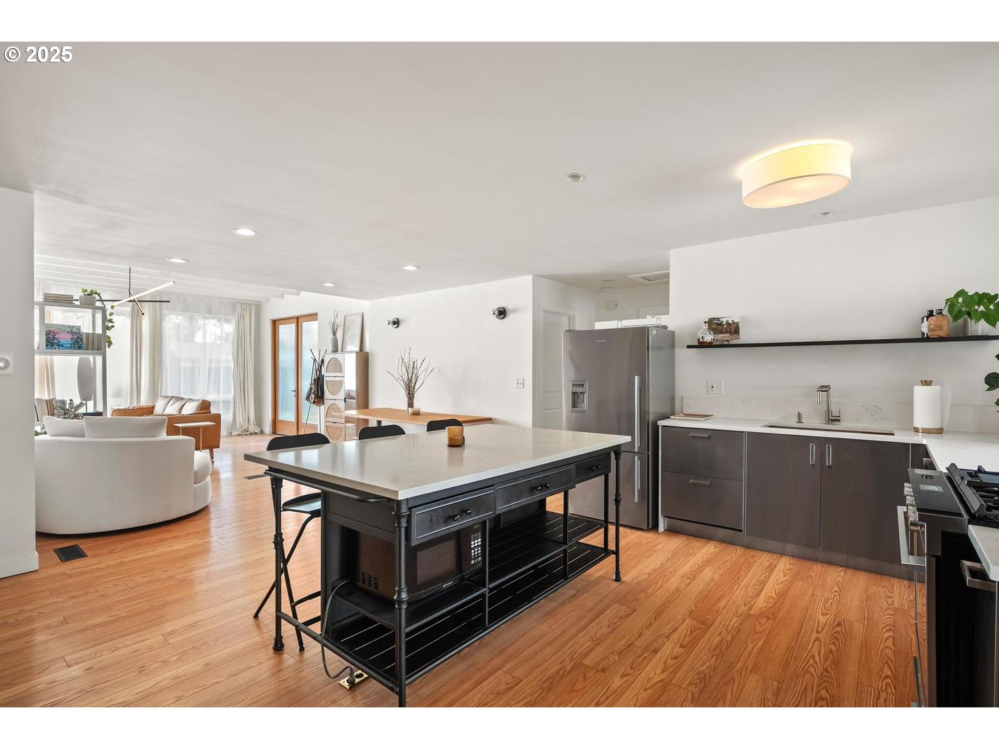8629 Northeast Clackamas Street Portland, OR 97220 - Photo 18 of 32 a kitchen with stainless steel appliances granite countertop a stove a refrigerator a sink and a dining table with wooden floor