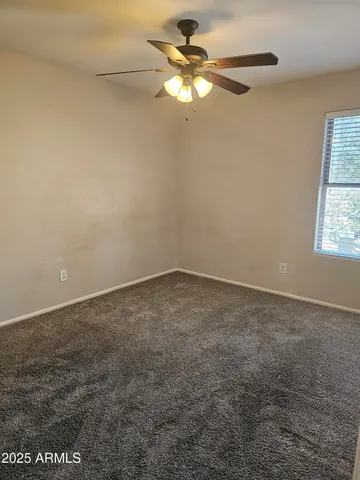 an empty room with a window and a fan