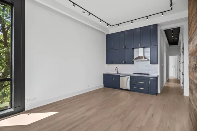 a large kitchen with stainless steel appliances granite countertop a refrigerator a sink dishwasher a stove and a dining table with wooden floor