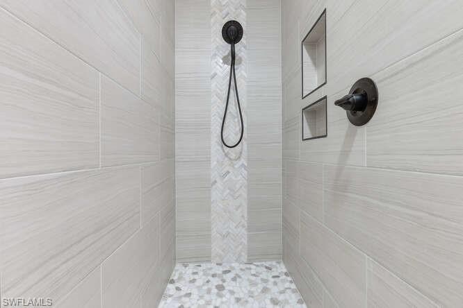 2876 West Crown Pointe Boulevard Naples, FL 34112 - Photo 14 of 36 Newly updated primary bath walk-in shower with a mix of decorative ceramic tile, built-in accessory holder and zero transition entry into bath area.