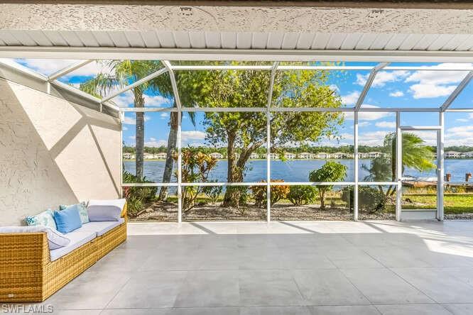 2876 West Crown Pointe Boulevard Naples, FL 34112 - Photo 21 of 36 Screened lanai featuring new tile flooring, electric storm shutter, ceiling fan, and a water view.