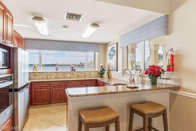 2876 West Crown Pointe Boulevard Naples, FL 34112 - Photo 26 of 36 Community Kitchen in the clubhouse featuring SS appliances, granite counters, and water views.