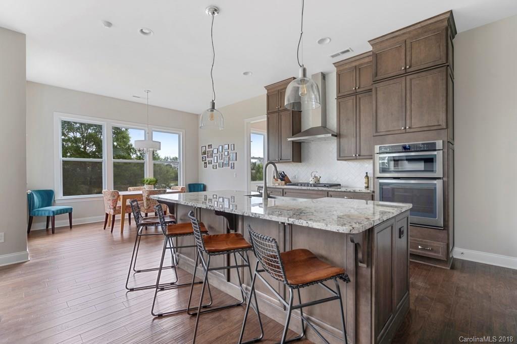 5354 Meadowcroft Way, Unit 56 Fort Mill, SC 29708 - Photo 8 of 36 a kitchen with stainless steel appliances granite countertop a stove a refrigerator a kitchen island a dining table and chairs with wooden floor