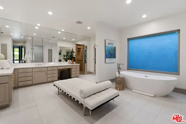 a bathroom with a large tub sink vanity and mirror