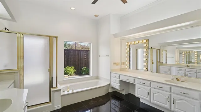 a bathroom with a double vanity sink a large mirror a bathtub and next to a window