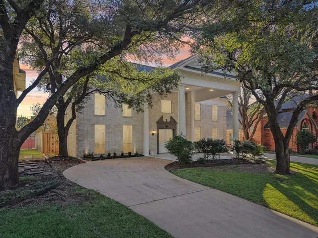 a front view of a house with a garden and trees