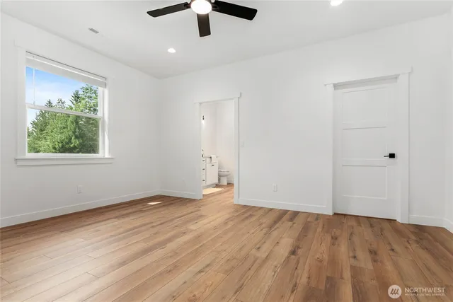 an empty room with wooden floor chandelier fan and windows