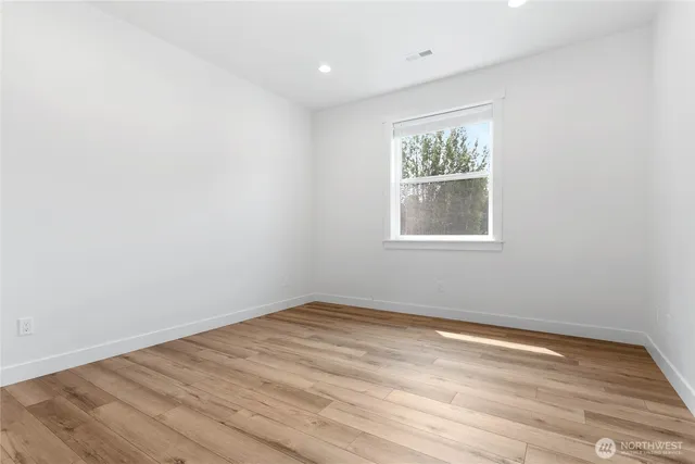 an empty room with wooden floor and window