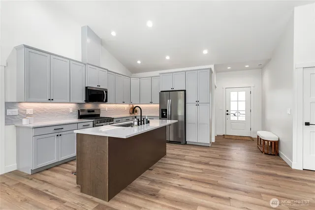 a kitchen with stainless steel appliances a sink stove refrigerator and cabinets