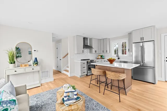 a kitchen with stainless steel appliances granite countertop a refrigerator a stove a sink dishwasher and white cabinets with wooden floor