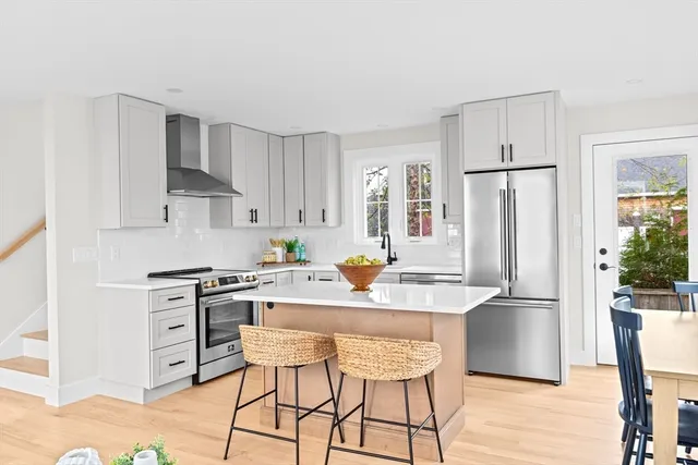 a kitchen with stainless steel appliances granite countertop a refrigerator a stove a sink a dining table and chairs