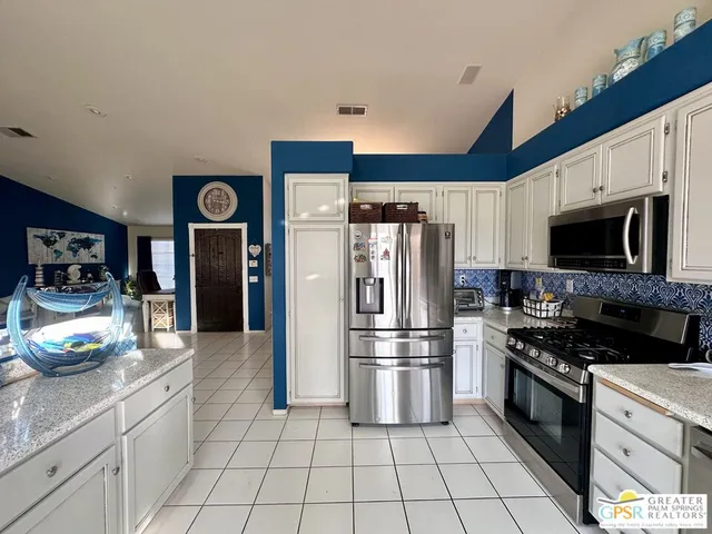 a kitchen with granite countertop a refrigerator and a stove top oven