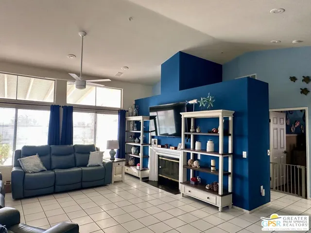 a living room with furniture a ceiling fan and a book shelf