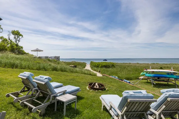 a view of a swimming pool and lounge chairs in back yard of the house