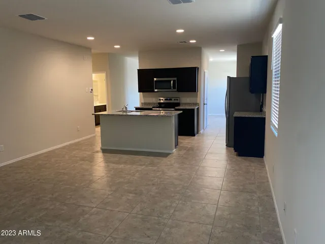 a view of kitchen with stainless steel appliances kitchen island empty cabinets and wooden floor