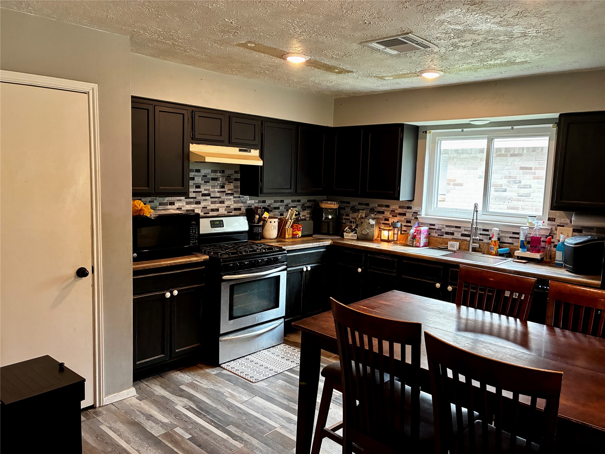 2 Sarita Road Angleton, TX 77515 - Photo 5 of 21 a kitchen with stainless steel appliances granite countertop a stove a sink dishwasher a dining table and chairs with wooden floor