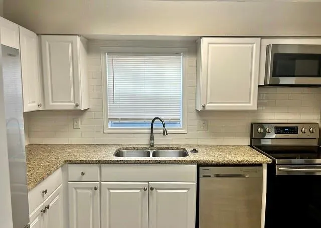 a kitchen with stainless steel appliances granite countertop a sink stove and microwave