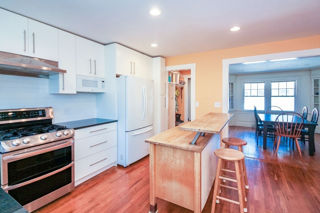 20 Stoneleigh Road, Unit 20 Newton, MA 02465 - Photo 3 of 30 a open kitchen with stainless steel appliances granite countertop a stove a refrigerator a kitchen island a hardwood floor and a sink