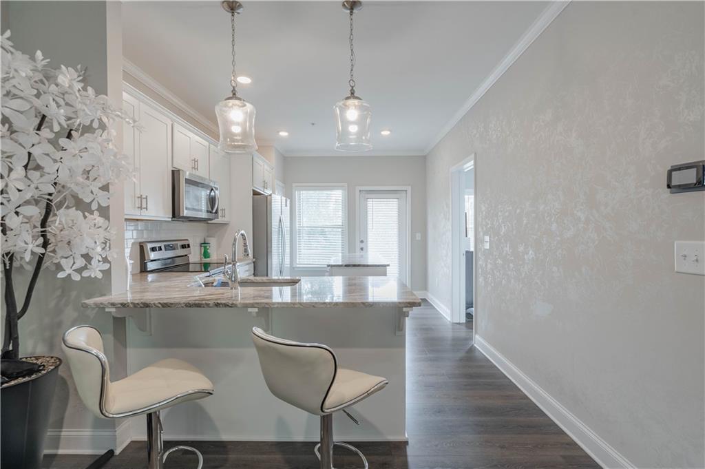 3110 Quantum Lane, Unit 53 Atlanta, GA 30341 - Photo 10 of 38 a kitchen with stainless steel appliances granite countertop a sink a stove a refrigerator dining table and chairs with wooden floor
