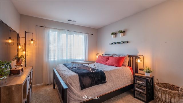 a bedroom with a bed and a flat tv screen on dresser